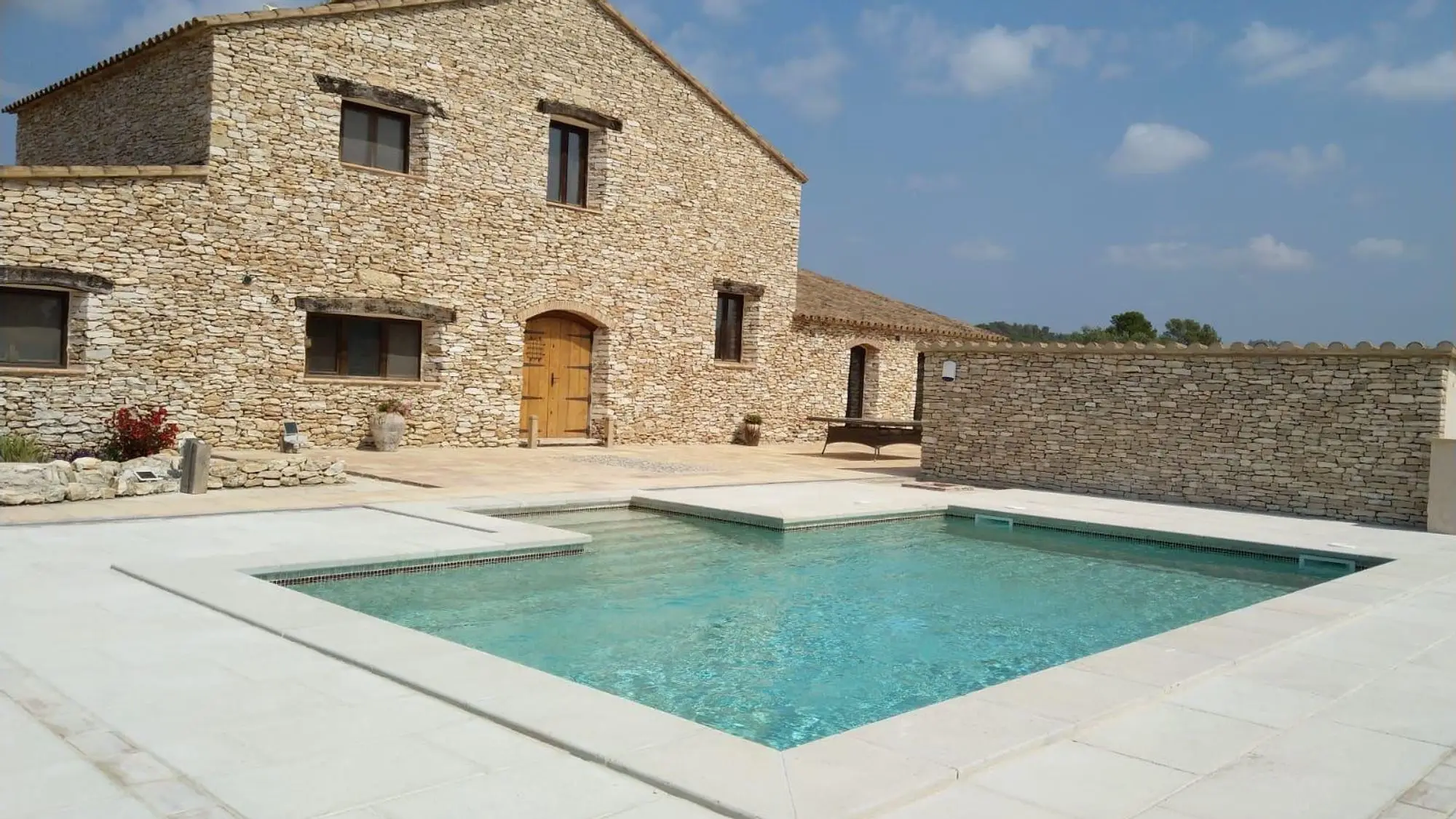 Masia de pedra amb la piscina i el paviment clar
