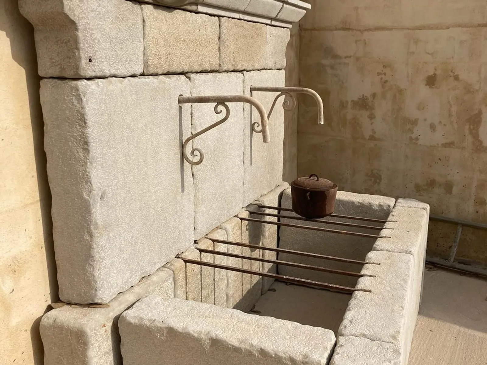 Font de paret de pedra blanca amb el frontal esculpit