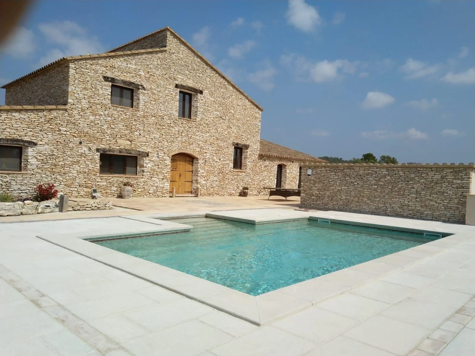 Masia de pedra amb una piscina i el paviment clar al voltant