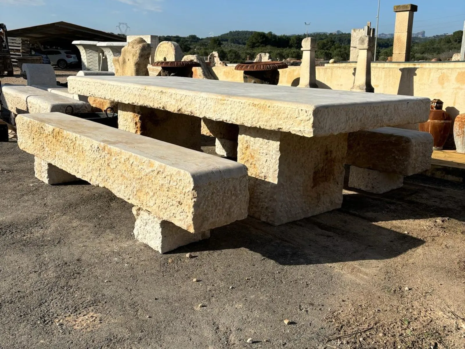 Taula llarga de pedra amb dos bancs, a l’exterior