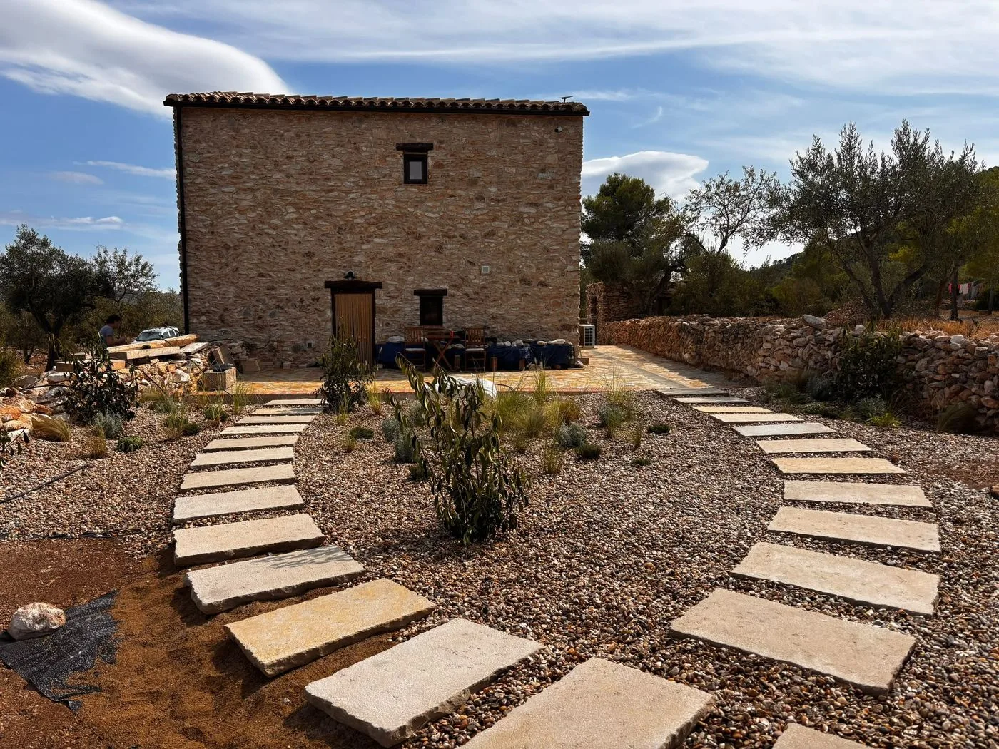 Masia de pedra amb dos camins de lloses que hi conflueixen